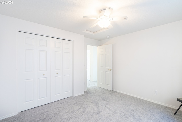 unfurnished bedroom with ceiling fan, a closet, and light carpet