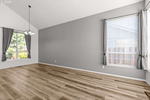 unfurnished room featuring hardwood / wood-style flooring, high vaulted ceiling, and an inviting chandelier