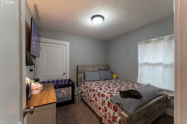 bedroom with a textured ceiling and dark carpet