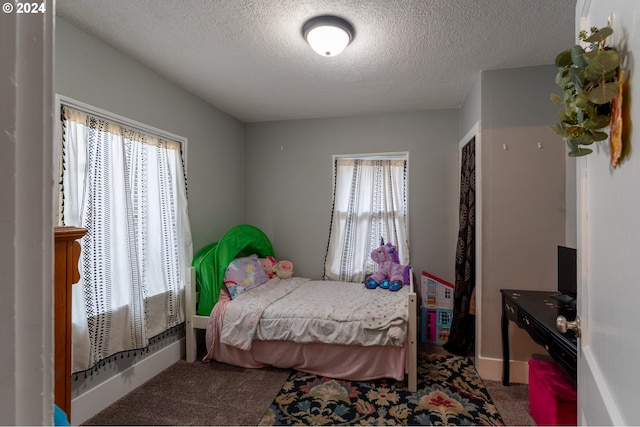 bedroom with carpet, a textured ceiling, and multiple windows