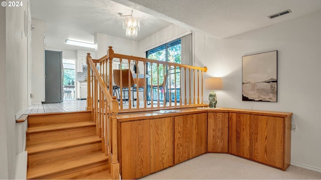 staircase featuring an inviting chandelier and a textured ceiling