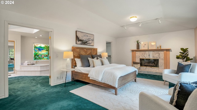 bedroom featuring dark carpet, a skylight, a fireplace, and rail lighting