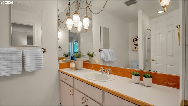 bathroom featuring vanity, a chandelier, and toilet