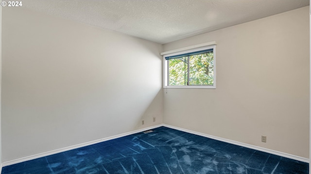 empty room with dark carpet and a textured ceiling