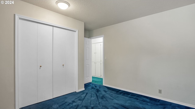 unfurnished bedroom with a textured ceiling, a closet, and dark colored carpet