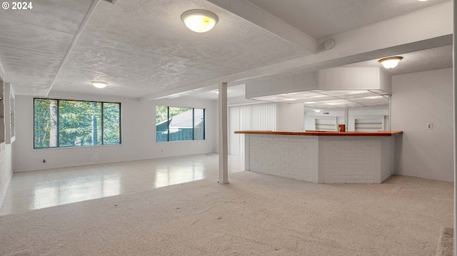 interior space featuring a textured ceiling, indoor bar, and light colored carpet