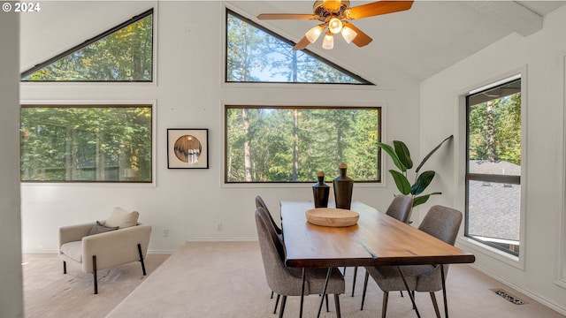 dining room with ceiling fan, light colored carpet, high vaulted ceiling, and a wealth of natural light