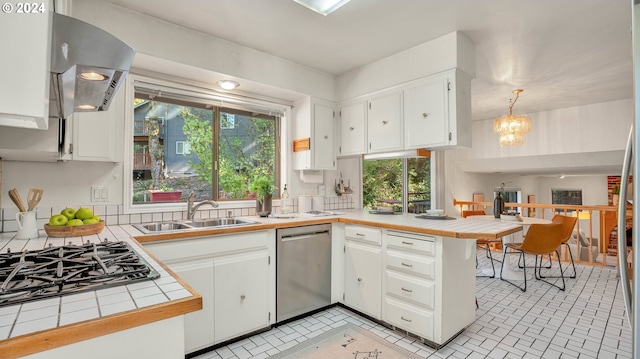 kitchen featuring tile countertops, kitchen peninsula, hanging light fixtures, appliances with stainless steel finishes, and white cabinetry