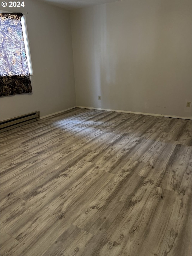 empty room with a baseboard heating unit and hardwood / wood-style floors