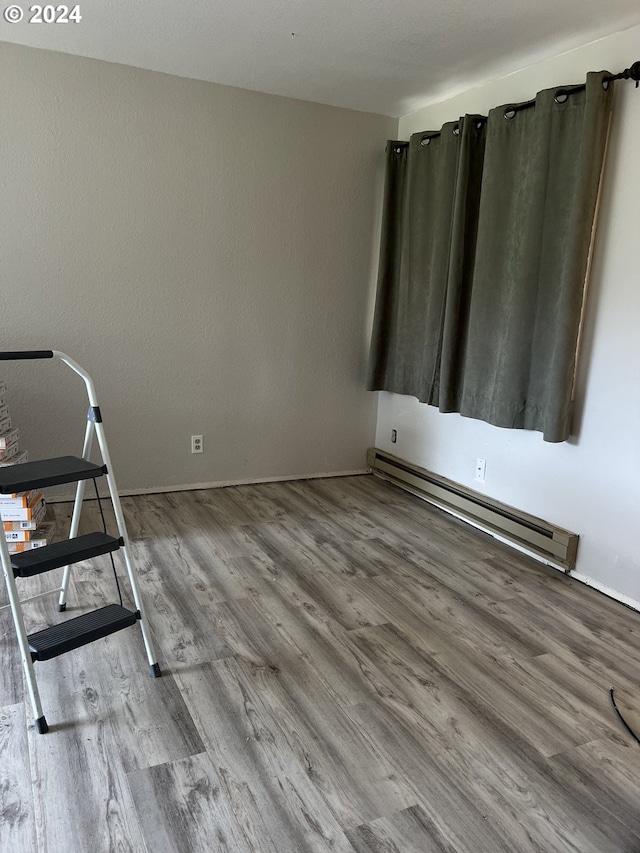 unfurnished room with a baseboard radiator and hardwood / wood-style floors