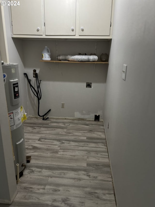 clothes washing area with electric water heater, washer hookup, cabinets, hookup for an electric dryer, and light wood-type flooring