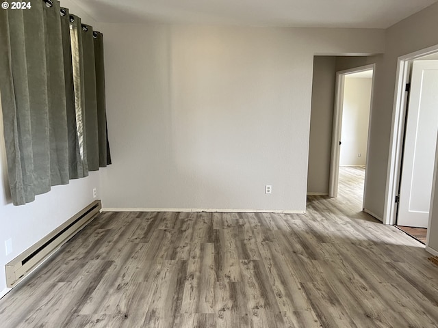 spare room with a baseboard heating unit and light hardwood / wood-style floors