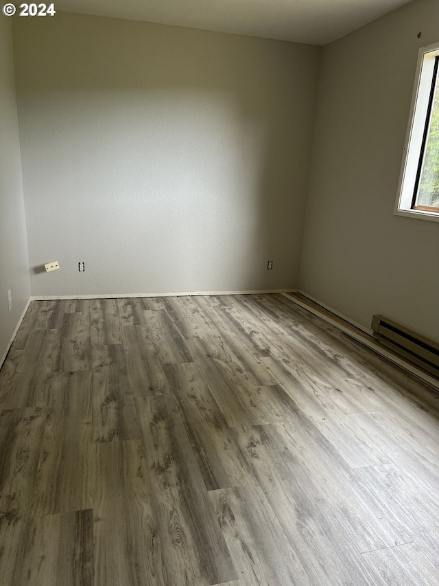 empty room with baseboard heating and hardwood / wood-style floors