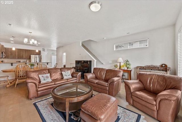 living area with a chandelier, a textured ceiling, and stairs