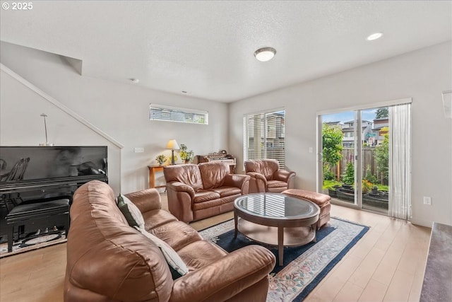 living area with healthy amount of natural light, a textured ceiling, light wood-type flooring, and recessed lighting