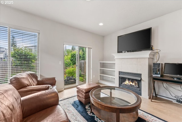 living room with a tiled fireplace, wood finished floors, and recessed lighting