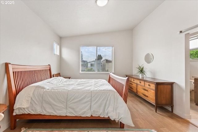 bedroom with lofted ceiling, multiple windows, and light wood-type flooring