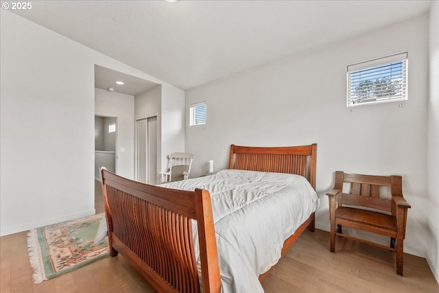 bedroom with wood finished floors, recessed lighting, baseboards, and a closet