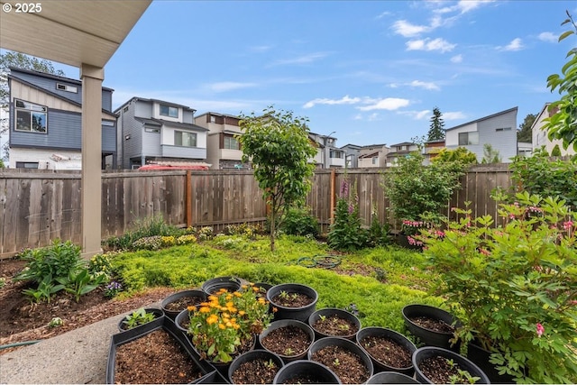 fenced backyard with a residential view and a garden