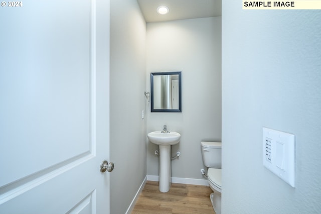 half bath with recessed lighting, wood finished floors, toilet, and baseboards