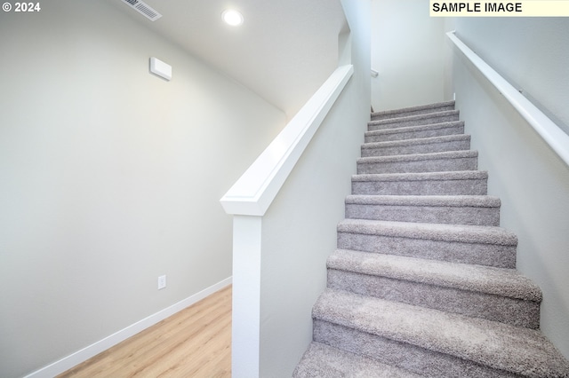 stairway with visible vents, baseboards, wood finished floors, and recessed lighting