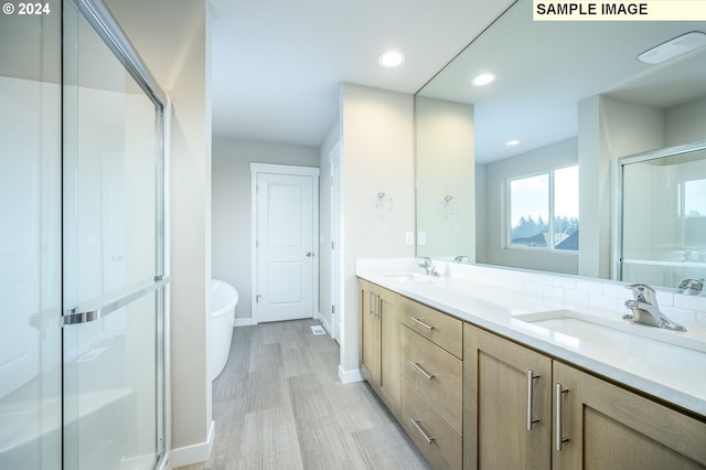 bathroom with recessed lighting, a sink, a shower stall, and double vanity