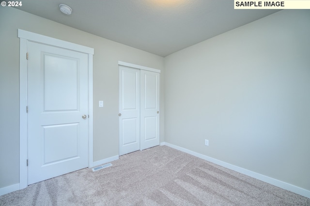 unfurnished bedroom with baseboards, visible vents, a closet, and light colored carpet