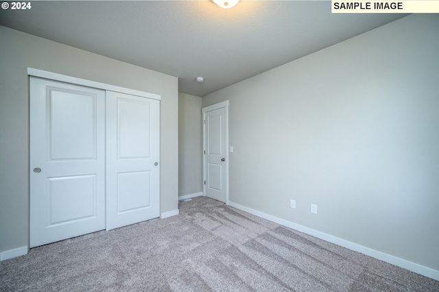 unfurnished bedroom featuring baseboards, a closet, and light colored carpet