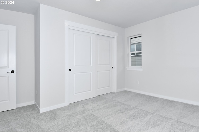 unfurnished bedroom featuring a closet and light colored carpet