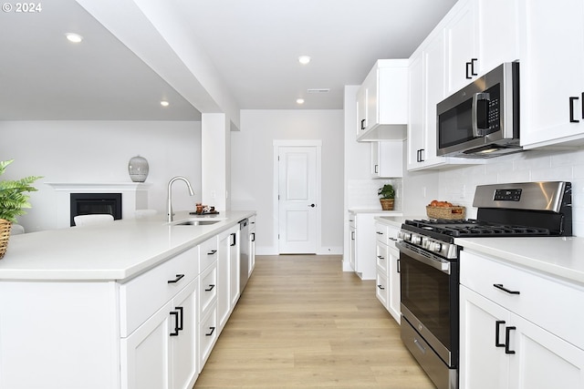 kitchen featuring light hardwood / wood-style flooring, backsplash, sink, white cabinetry, and appliances with stainless steel finishes