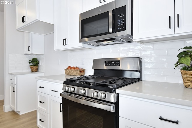 kitchen with light hardwood / wood-style flooring, tasteful backsplash, white cabinetry, and appliances with stainless steel finishes