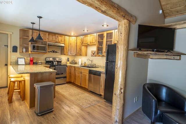 kitchen with kitchen peninsula, a kitchen breakfast bar, light wood-type flooring, stainless steel appliances, and hanging light fixtures