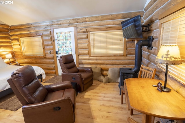 sitting room with light hardwood / wood-style floors, a wood stove, and rustic walls