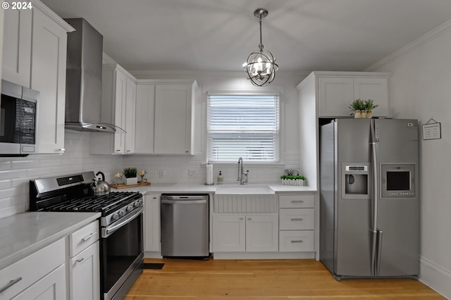 kitchen featuring sink, a notable chandelier, white cabinetry, wall chimney exhaust hood, and appliances with stainless steel finishes