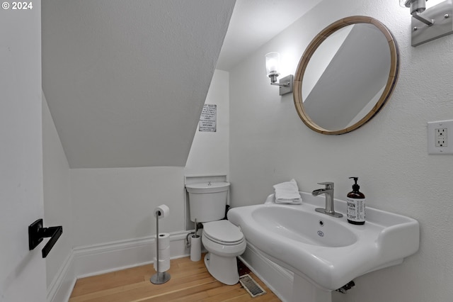 bathroom with wood-type flooring, vaulted ceiling, sink, and toilet