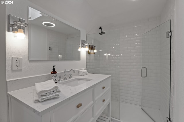 bathroom featuring vanity, a shower with shower door, and vaulted ceiling