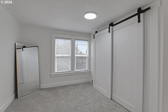 spacious closet featuring light carpet and a barn door