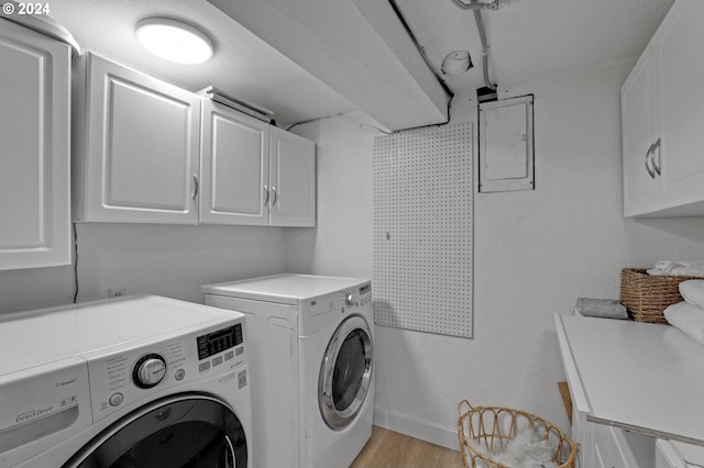 laundry area with cabinets, light hardwood / wood-style flooring, and washing machine and dryer