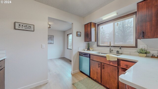 kitchen featuring sink, stainless steel dishwasher, a textured ceiling, and light hardwood / wood-style flooring