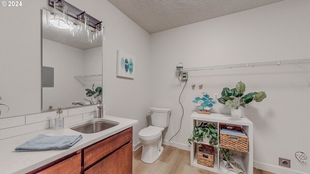 bathroom featuring a textured ceiling, toilet, vanity, and hardwood / wood-style flooring