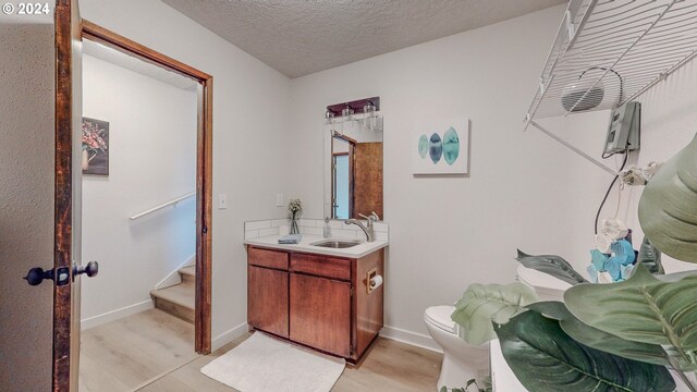 bathroom featuring hardwood / wood-style flooring, toilet, vanity, and a textured ceiling