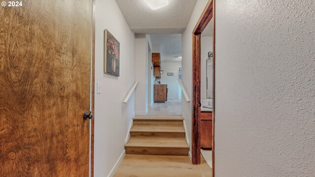 staircase featuring wood-type flooring and a textured ceiling