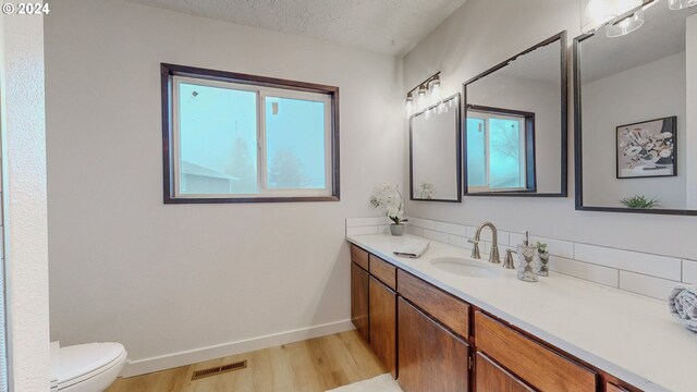 bathroom featuring a textured ceiling, toilet, vanity, and hardwood / wood-style floors