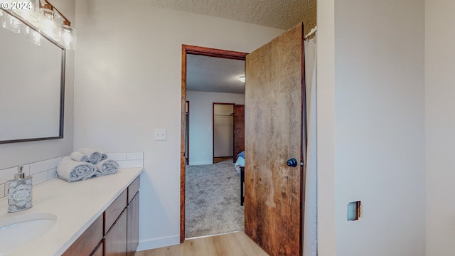 bathroom featuring wood-type flooring, vanity, and a textured ceiling