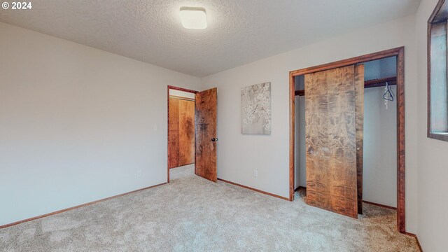 unfurnished bedroom featuring a closet, light carpet, and a textured ceiling