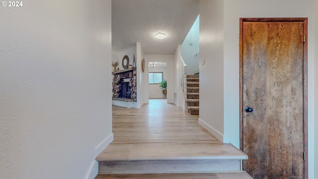 corridor with a textured ceiling and light hardwood / wood-style floors