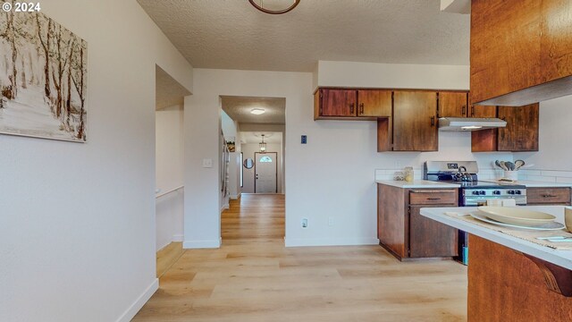 kitchen featuring a textured ceiling, electric range, and light hardwood / wood-style floors