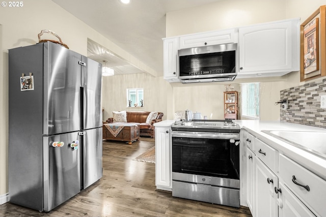 kitchen featuring appliances with stainless steel finishes, white cabinetry, backsplash, and wood-type flooring