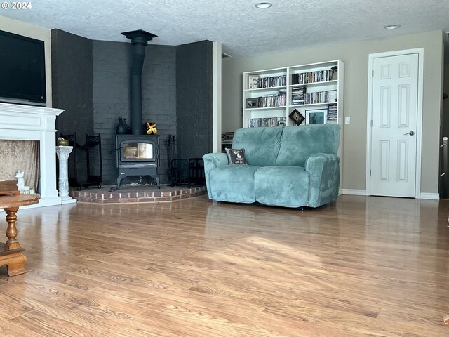 living room featuring hardwood / wood-style floors, a wood stove, and a textured ceiling