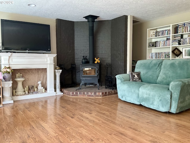 living area with a wood stove, a textured ceiling, and light hardwood / wood-style flooring